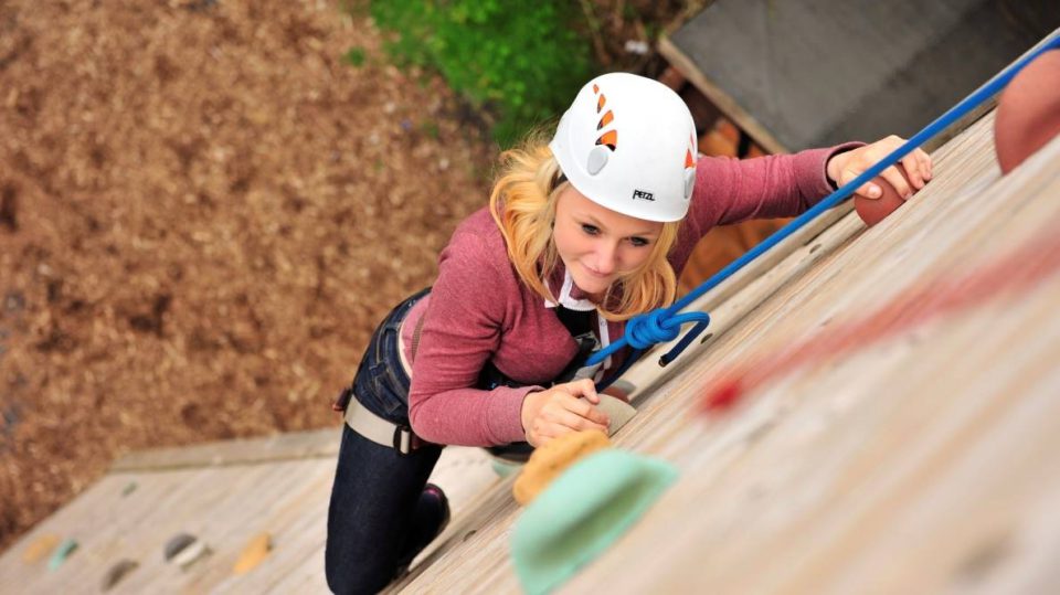 Looking down at a woman climbing up a wall