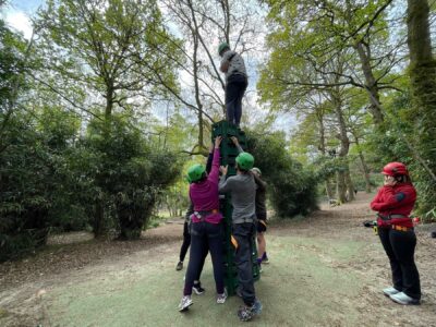 A person stood on top a a stack of crates with people stood around them