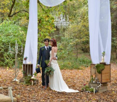 A bride and groom pose for photographs in a forest