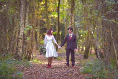 A bride and groom holding hands in a forest