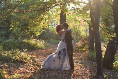 A bride and groom pose for photographs in a forest