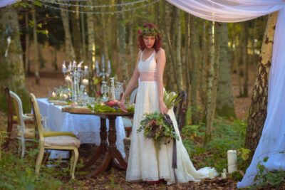 A bride poses for photographs in a forest