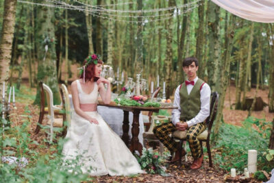 A bride and groom sat at a table in a forest
