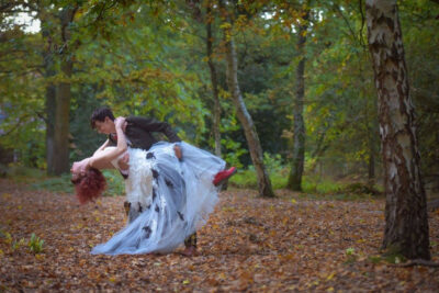 A bride and groom pose for photographs in a forest